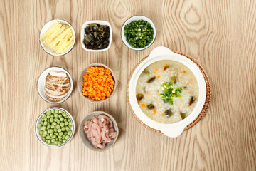 Pork Congee with Eggs and Vegetable Toppings on Wooden Table - Traditional Asian Rice Porridge Meal