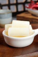 Fresh butter slices in white ceramic bowl on wooden kitchen counter