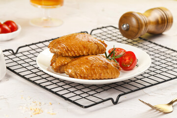 Delicious Golden Baked Chicken Wings with Salt Mill and Cherry Tomatoes on Marble Kitchen Counter