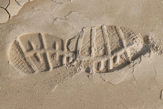 Footprint of a hiking boot creating a deep impression on the sand