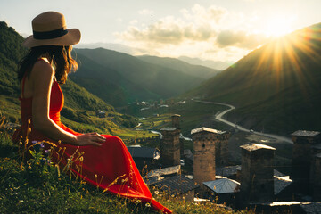 Tourist woman in red dress enjoy view of Ushguli village in Georgia.