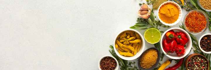 A mix of dried herbs and spices laid out on a gray background, highlighting natural flavors and culinary essentials, top view and copy space, banner