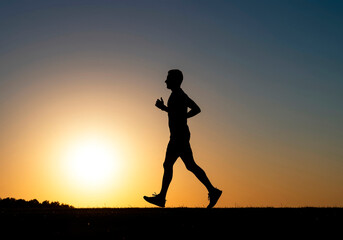 Silhouette of man running outdoors at sunset, concept of fitness, healthy lifestyle, outdoor exercise, wellness, cardio training, sport activity and motivation