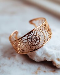 Naklejka premium Elegant gold bracelet with filigree spiral design on marble surface for fashion and jewelry display