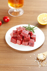 Fresh Raw Beef Diced into Cubes with Herbs and Seasonings on Wooden Board