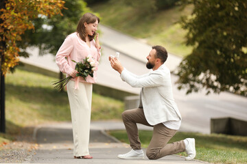 Fototapeta premium Man with engagement ring making marriage proposal to his girlfriend outdoors