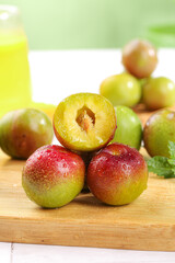Fresh Ripe Plums Cut in Half Showing Golden Flesh on Wooden Cutting Board