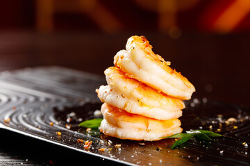 Pan-Fried Shrimp Stack with Salt and Herbs on Dark Slate Plate - Gourmet Seafood Cuisine