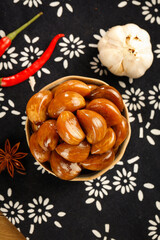 Chinese Soy Sauce Braised Garlic Side Dish with Spices on Traditional Black Fabric - Guangxi Cuisine