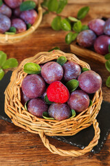 Fresh Ripe Plums in Wicker Basket with Red Heart Flesh Ready to Pick on Wooden Background