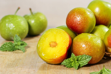 Fresh Cut Plums with Yellow Pulp and Mint Garnish on Wooden Background