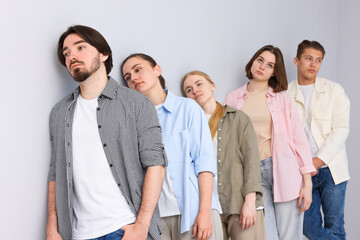 Fototapeta premium Group of people waiting in queue near light grey wall indoors