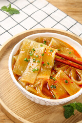 Spicy Szechuan Hot Pot with Wide Rice Noodles and Chopsticks in Traditional Bowl