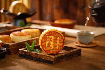 Traditional Chinese Mooncakes with Red Bean and Egg Yolk on Wooden Base with Tea