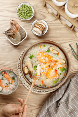 Fresh Shrimp Congee with Seasonal Vegetables and Peas on Wooden Table - Traditional Asian Rice Porridge Meal