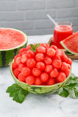 Fresh Watermelon Balls Display in Melon Bowl with Red Juice and Mint Garnish on White Marble Surface
