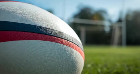 Starting camera lens shifting focus on white rugby ball on grass pitch with goalpost, copy space - Powered by Adobe
