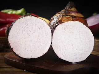 Sliced Fresh Taro Root with Purple Speckled White Flesh on Wooden Cutting Board