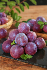 Freshly picked red sanhua plums with heart-shaped arrangement and mint garnish on wooden table