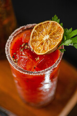 A classic Bloody Mary cocktail served in a crystal glass with salted rim, ice cubes, and garnished...