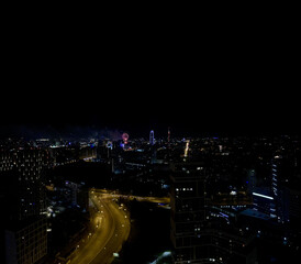 Aerial view of modern city at night with fireworks, urban skyline illuminated, celebration scene, vibrant night lights, holiday event, festive atmosphere, cityscape drone footage, night city lights