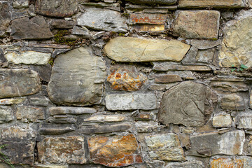 Ancient weathered stone wall with plants and moss, abstract backdrop