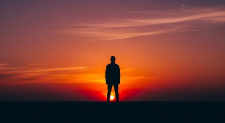 Fototapeta premium Silhouette of a person against a vibrant sunset.