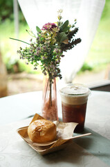 Delicious snack with refreshing iced coffee on the table with decorative flowers. The scene evokes a sense of leisure and comfort, perfect for a relaxing break
