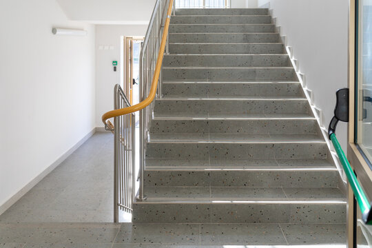 Modern indoor staircase with speckled steps and safety railings. Functional architecture for schools, hospitals or offices. - Powered by Adobe