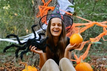 A joyful celebration of Halloween features a person wearing a witch hat, holding pumpkins and a...