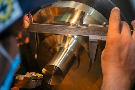 Close up scene the machine operator measuring dimension of metal shaft parts by Vernier caliper.