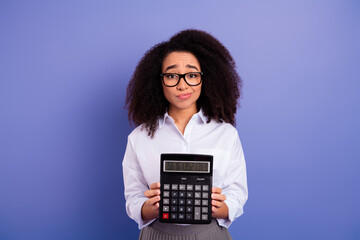 Lovely professional woman holding a calculator in front of violet background, wearing stylish...