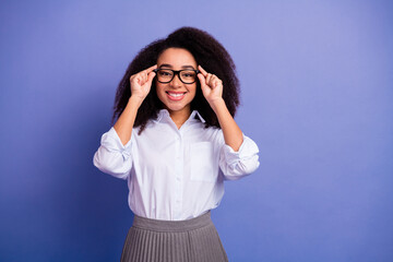 Portrait of a young woman wearing glasses smiling with a confident pose on a vibrant purple...