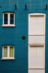 Obraz premium Blue Brick Wall with White Windows and Shutters