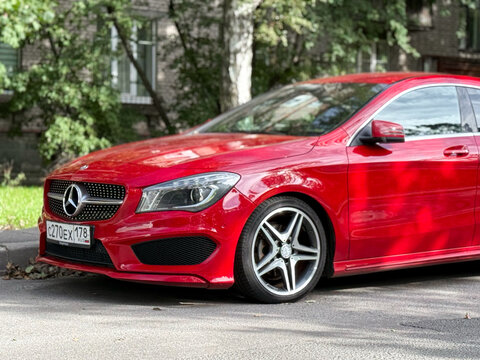A red sedan Mercedes-Benz CLA-Class CLA 200 DCT 4MATIC AMG Line  parked on street. Exterior of a red sedan German manufacturer Mercedes Benz CLA 200. 
