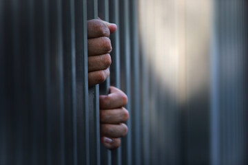 Hands Grasping Bars of Jail Cell Symbolizing Confinement and Despair
