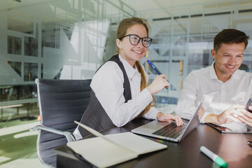 Business professionals engaged in collaborative work in a modern office setting with computers and notepads