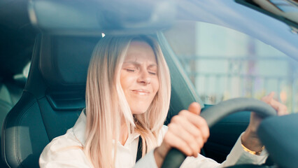 Cheerful Young Woman is Happily Driving in Her Car, Fully Experiencing True Joy and Freedom. Female is enjoying a thrilling driving experience, showcasing pure joy and excitement in every way possible