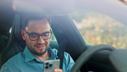 A Man is Actively Using His Smartphone While He is Driving in a Vehicle on the Road. A focused male enjoying his phone while sitting in a car, exemplifying modern tech usage and lifestyle