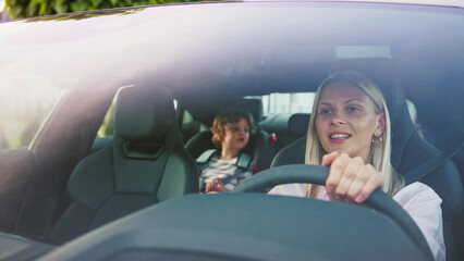 A joyful mother drives her beloved child in a modern car, enjoying their outdoor journey