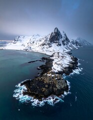 A breathtaking aerial view of a snow-capped coastline, showcasing rugged mountains and a serene icy sea.