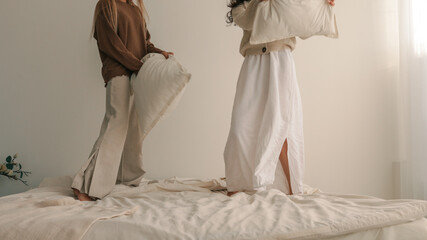 Joyful Pillow Fight in a Bright Bedroom