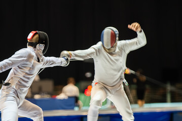 Fototapeta premium Two fencing athletes fight on professional sports arena