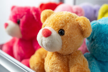 Toy claw machine filled with colorful teddy bears, isolated on white background.