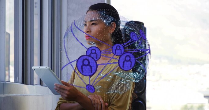 Woman in mustard blouse holding tablet at windows in office, with digital globe overlay and speaker
