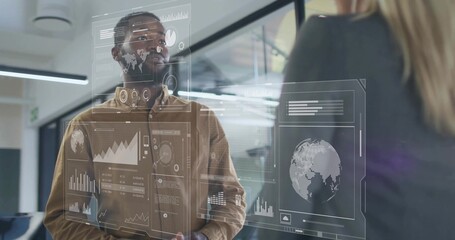 Male professional wearing brown shirt examining data overlays on glass partition in office