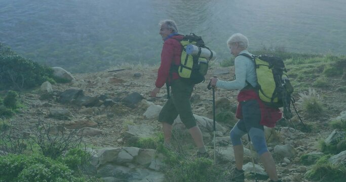 Climbing hiking couple ascending rocky lakeside trail, with backpacks and trekking poles - Powered by Adobe