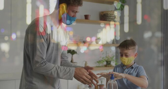 Guiding father and son wearing face masks practicing hand sanitizing on counter, with pump bottle - Powered by Adobe