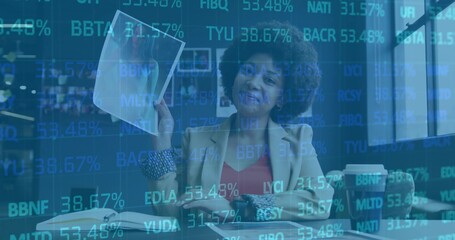 Reviewing businesswoman examining documents at office desk, with laptop coffee cup ticker overlay