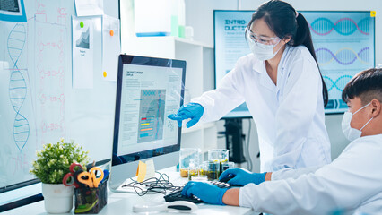 Scientists collaborating in a laboratory, with a female researcher presenting data on a computer...